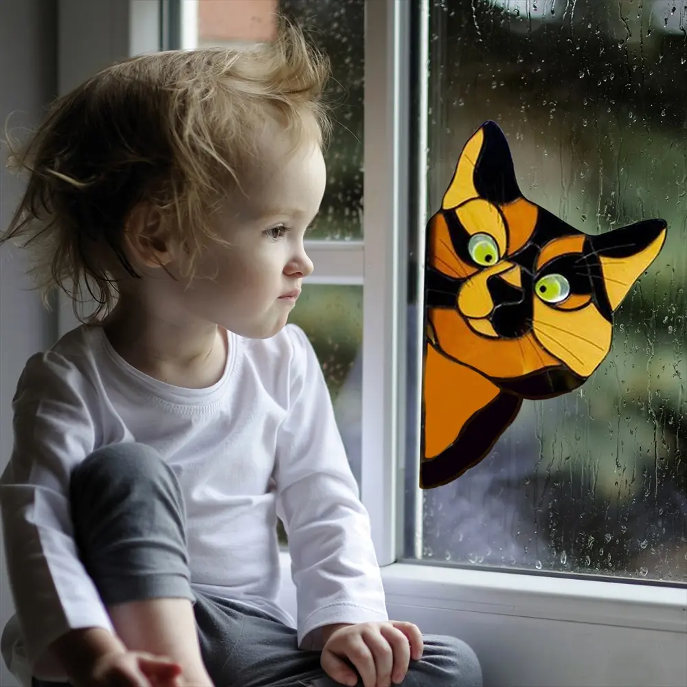 窓辺で読書する子どものそばに貼られたのぞき猫ステッカー