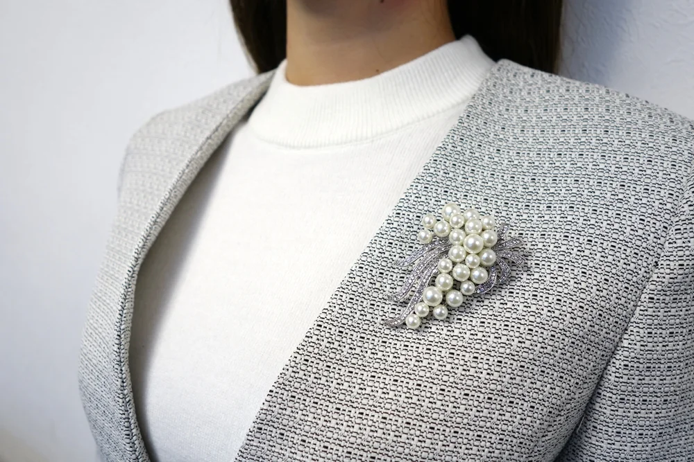 グレーツイードジャケットにパールブローチを着用したアップ