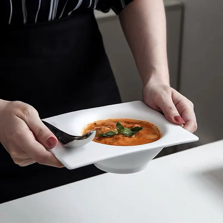 白いプレートにスープを盛り付けて持っているシーン